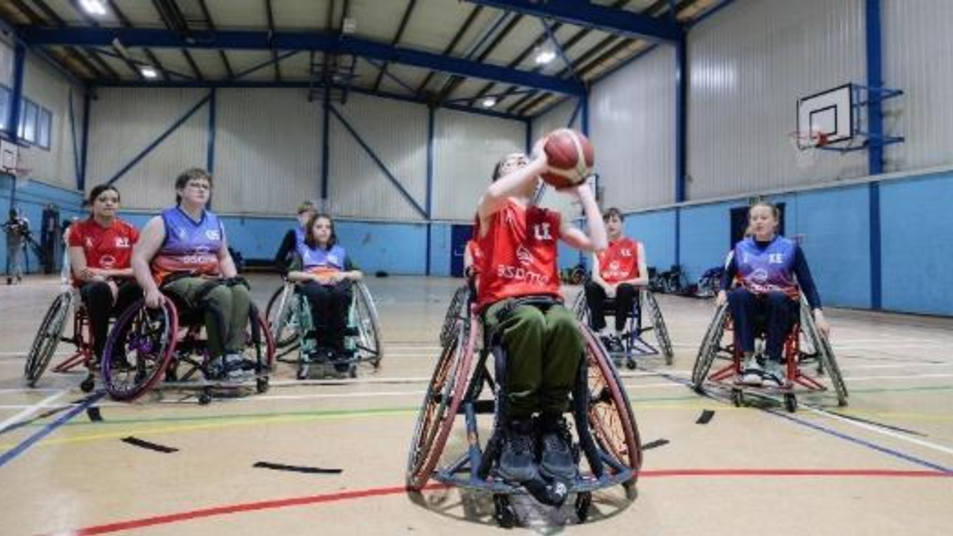 Young people playing wheelchair basketball in a sports hall